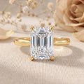 Emerald cut lab grown diamond engagement ring in 14K yellow gold solitaire setting on a white background.